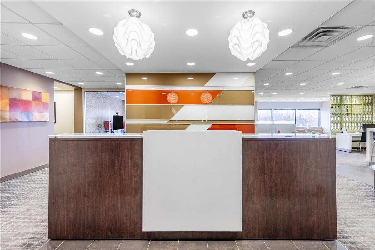 Reception desk at 150 Monument Road, 2nd Floor, featuring warm wood tones and modern lighting.