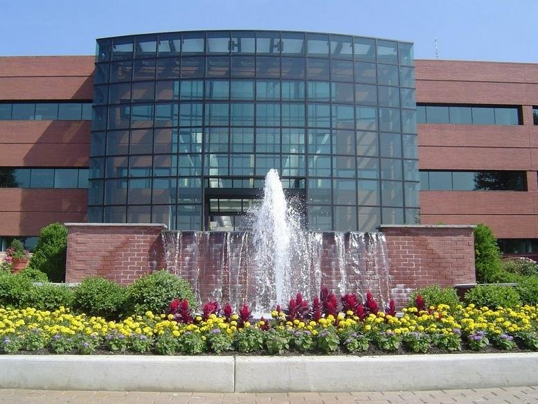 Exterior of the brick and glass-fronted Radnor Financial Building with a fountain and flower beds.