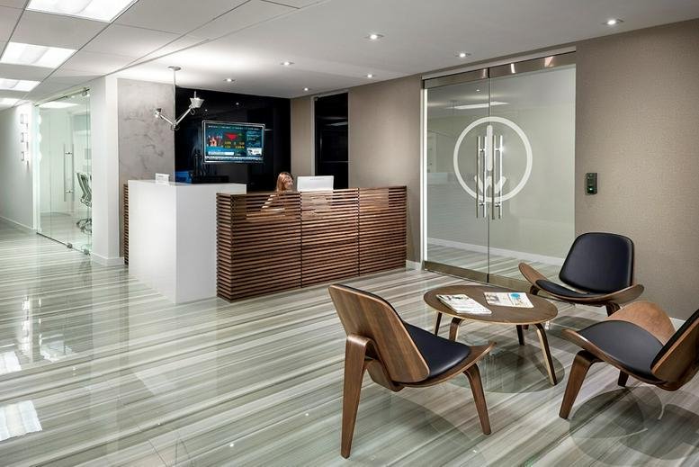 Modern reception area with a white and wood front desk and stylish lounge chairs.