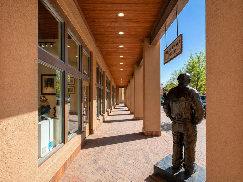 Covered outdoor walkway at Heritage Ascent with a sculpture and gallery windows.