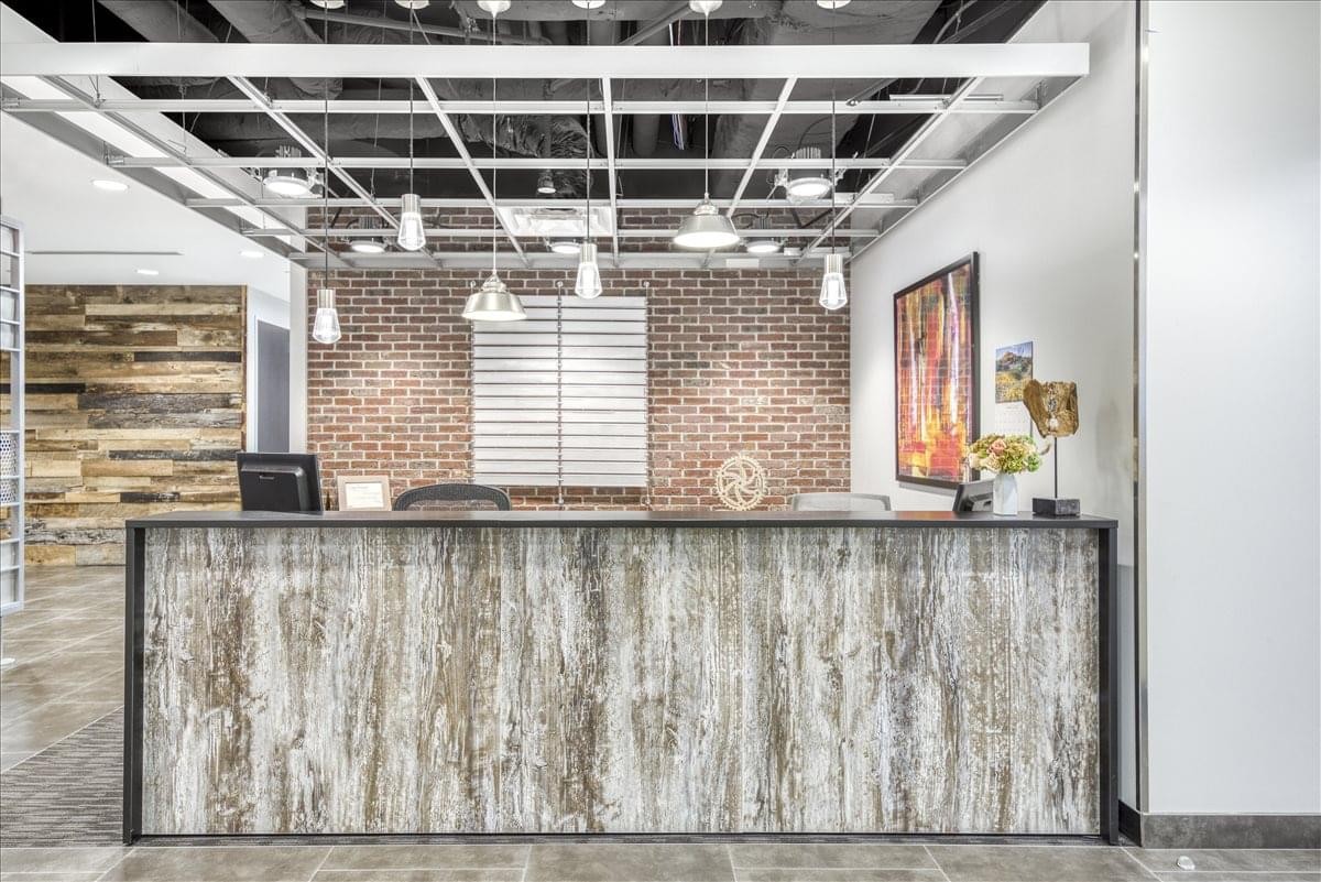 Reception area at Raintree Corporate Center with a wood-textured desk and industrial ceiling grid.