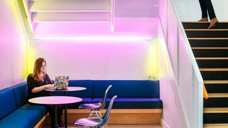 Spacious communal lounge at 154 W 14th Street with blue booth seating and pink neon lighting.