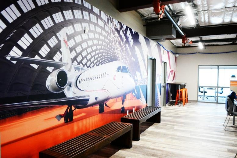Spacious communal lounge at 15492 Voss Road featuring a large aviation mural and wooden bench seating.