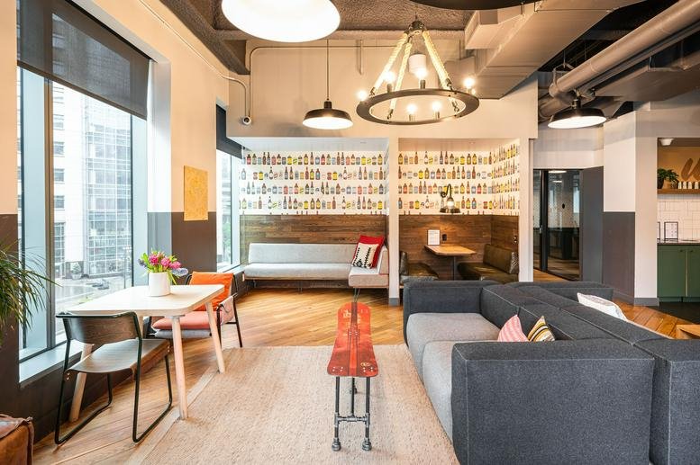Spacious lounge with a grey sectional sofa, wooden floors, and a modern chandelier.