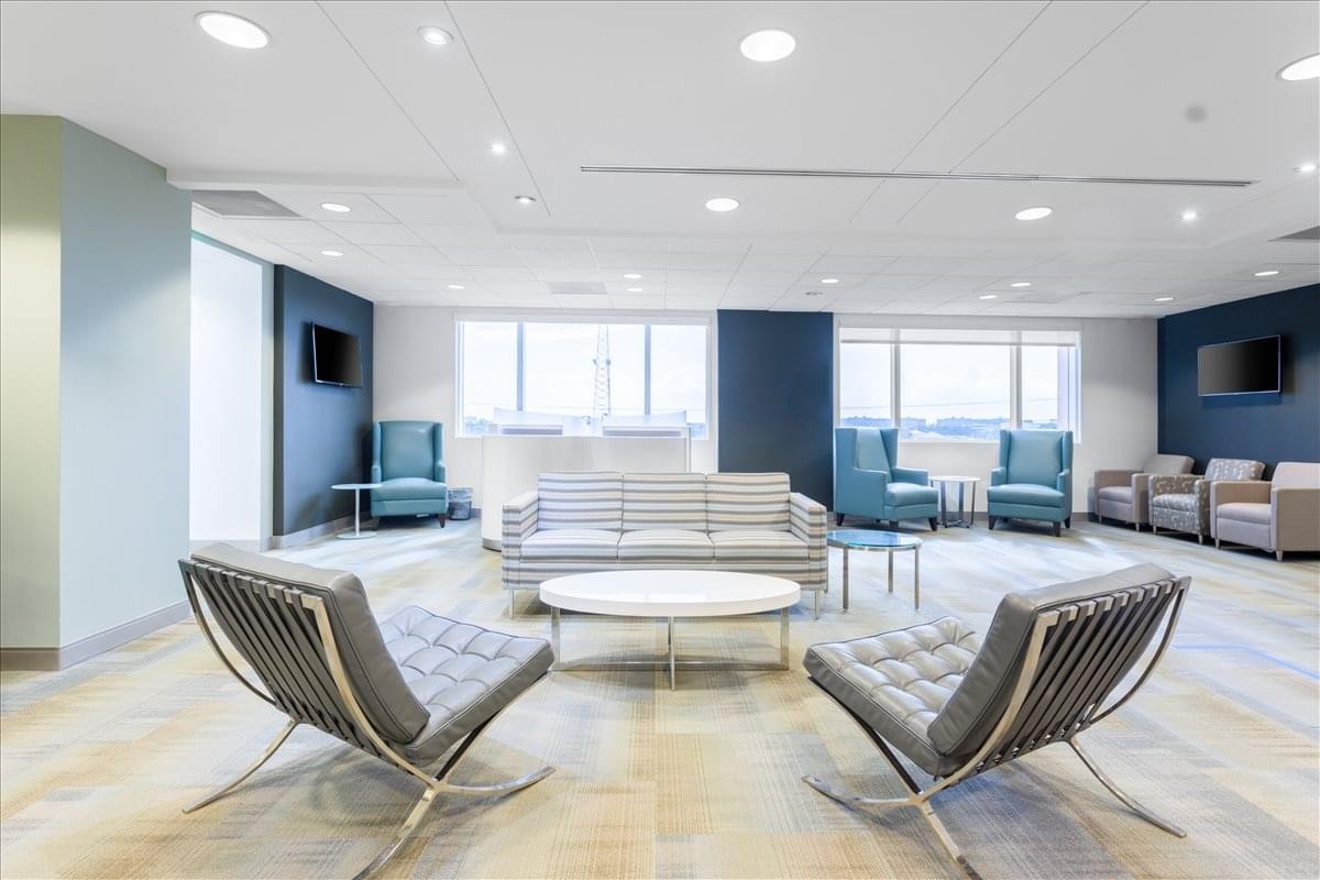 Modern lounge area with grey armchairs, a white coffee table, and blue accent pillars.