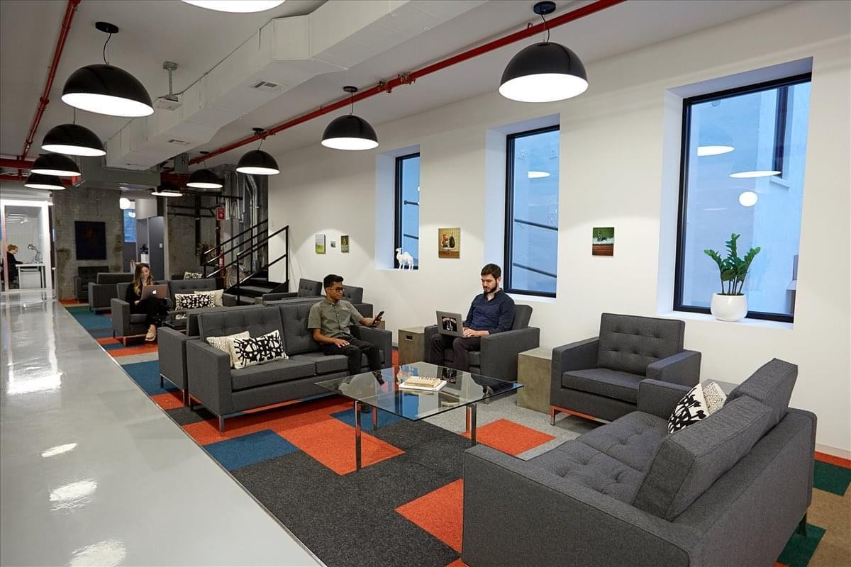Spacious lounge area at 157 13th Street, Gowanus, New York City with grey sofas and a colorful rug.