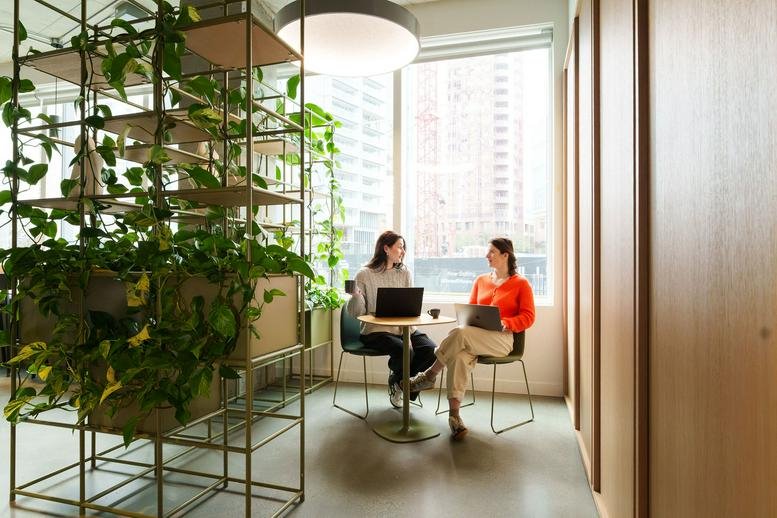 Bright breakout space at And-Co, 1575 West Georgia Street with tall plant shelving and city views.