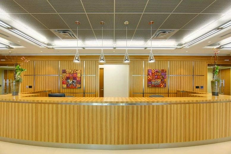 Spacious wood-paneled reception area with a curved desk and modern pendant lighting.