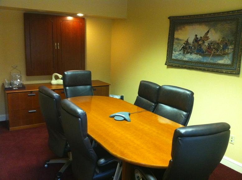 Wooden conference table at 1669 Edgewood Road with black leather chairs and a framed painting.