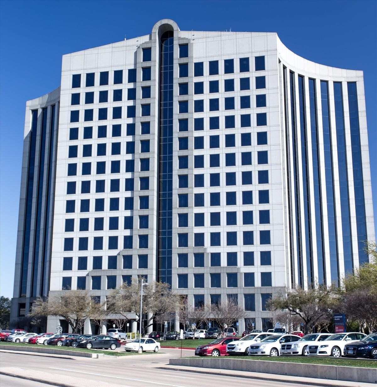 Exterior view of the multi-story Dominion Plaza building with its distinctive curved white facade and glass columns.