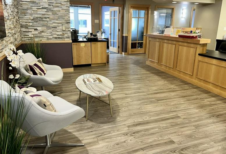 Reception area at 1775 I Street NW, Suite 1150, featuring wooden desks and white lounge chairs.