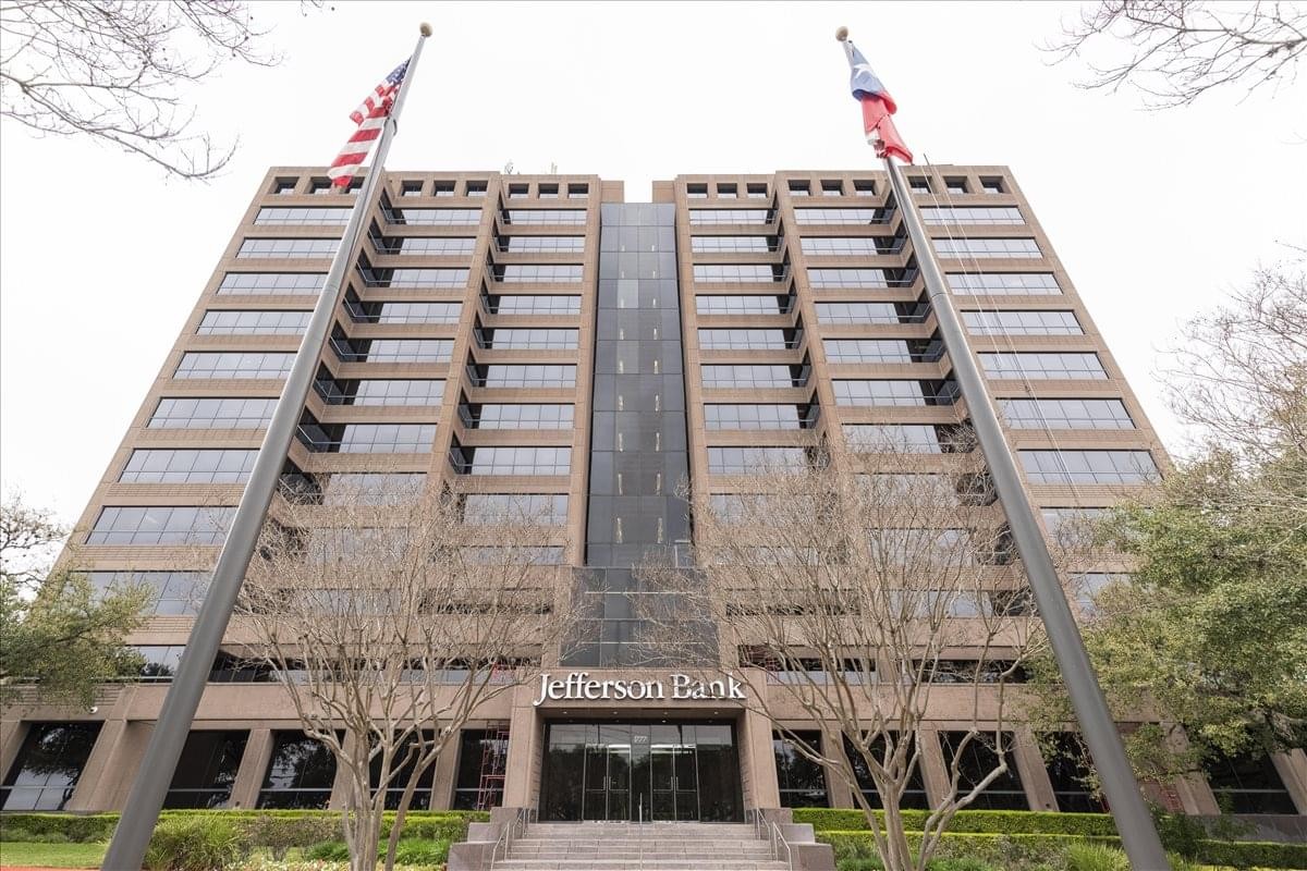 Exterior facade of the high-rise Airport Area Center with two American flags on top.