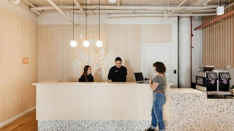 Spacious wood-paneled reception area at 18 West 18th Street, New York City with a marble-tiled desk and pendant lights.