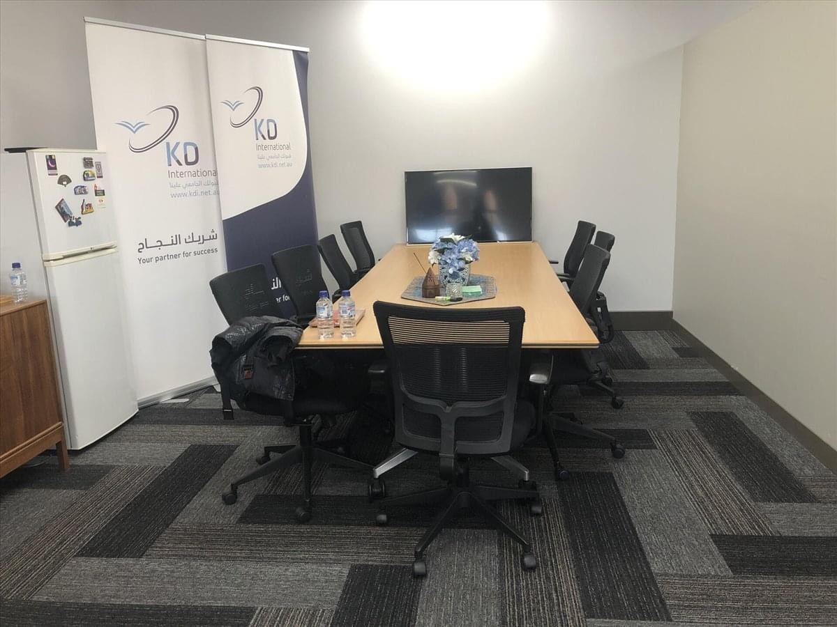 Meeting room at 180 John Street with a light wood table and black ergonomic chairs.