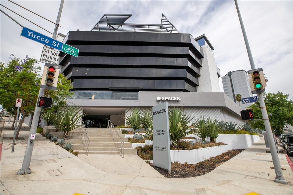 Modern black and white exterior of 1800 North Vine Street with tiered balconies and tropical greenery.