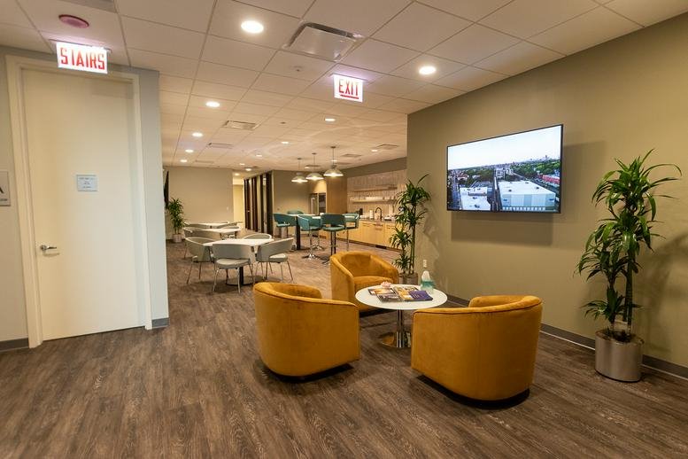 Modern reception lobby at 181 West Madison, Chicago with yellow armchairs and wall-mounted TV.