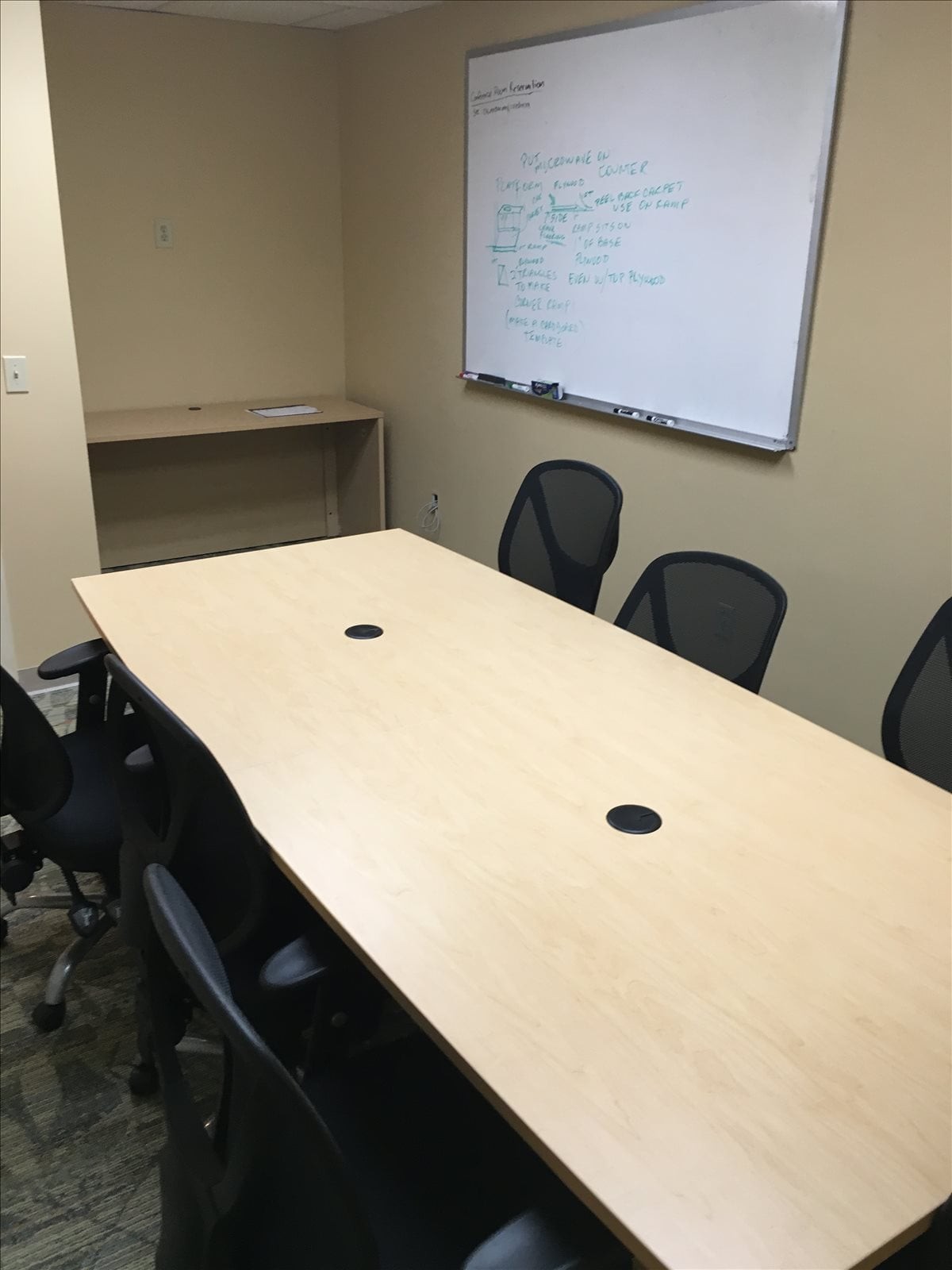 Spacious conference room with a large wooden table and a whiteboard at West Point Commons.