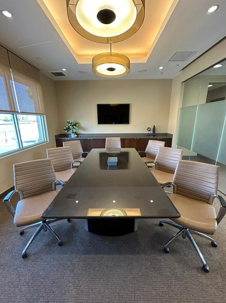 Modern conference room with a large dark table, leather chairs, and circular pendant lighting.