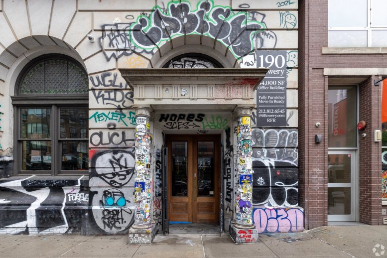 Exterior entrance of Industrious at 190 Bowery featuring a historic stone facade covered in colorful graffiti.