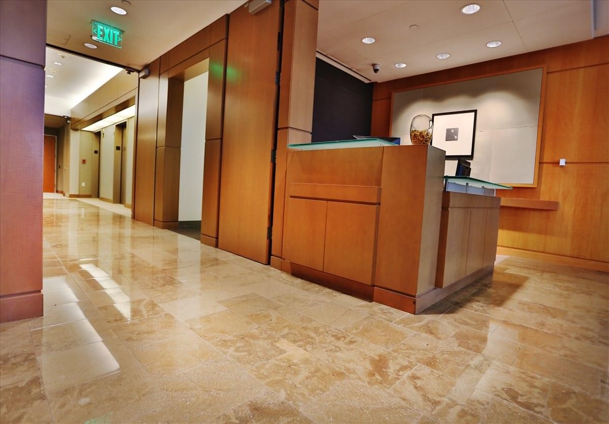 Bright reception area with wooden wall paneling and polished stone flooring.