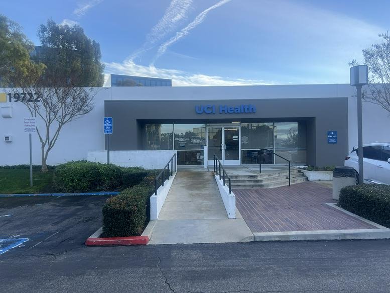Small conference room with a wooden table, black chairs, and a wall-mounted monitor.