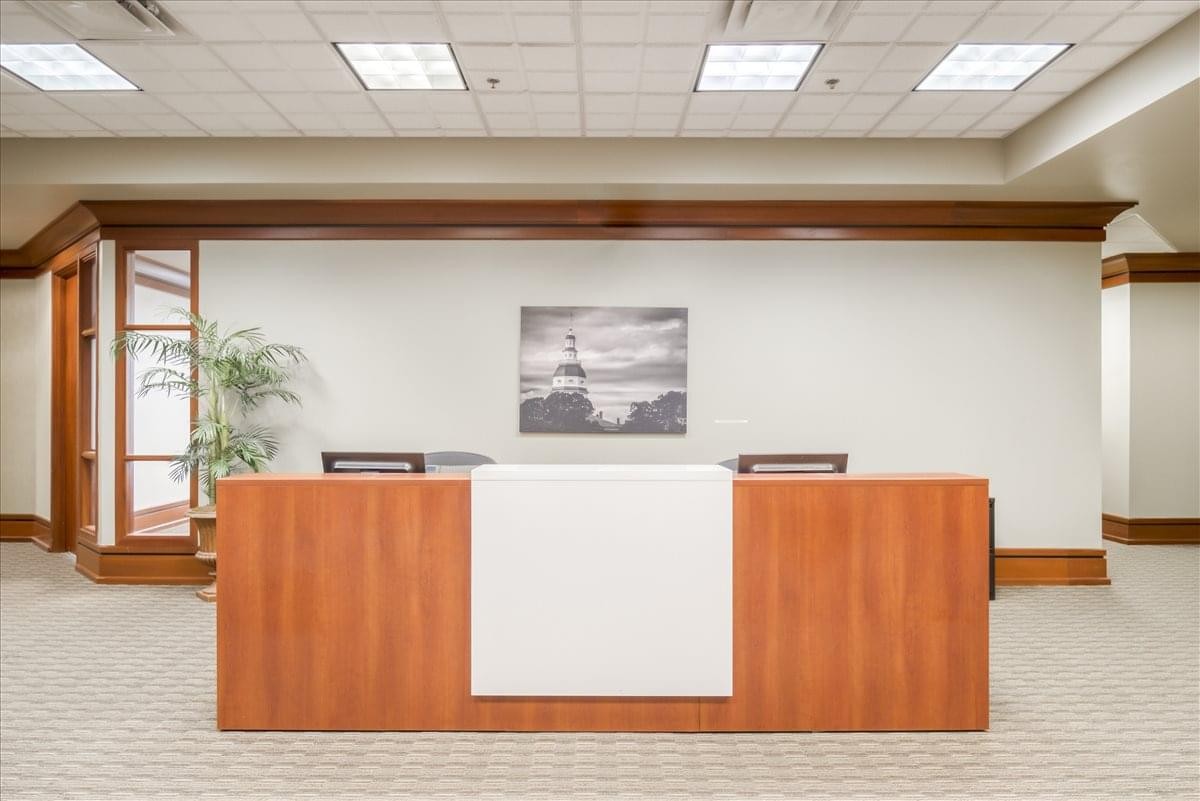 Reception desk at 1997 Annapolis Exchange Parkway, Suite 300, featuring warm wood paneling and a white center panel.