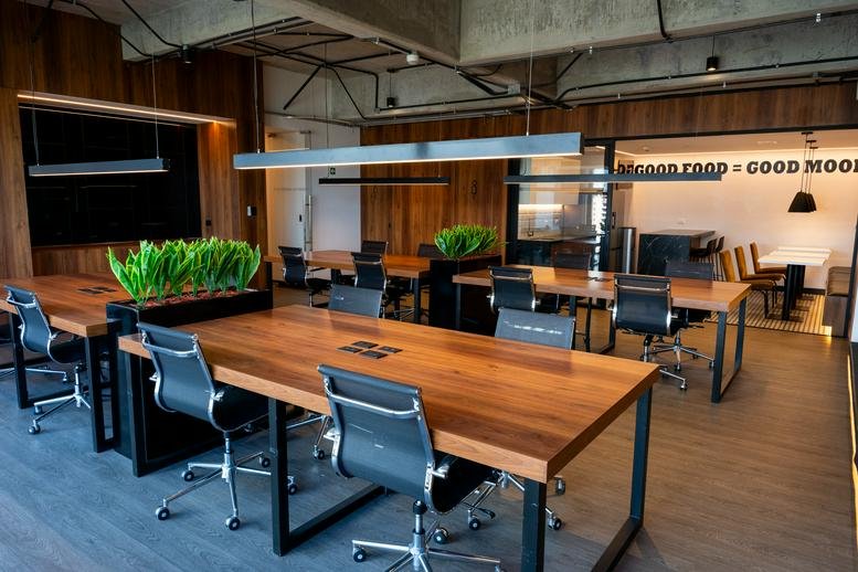 Spacious open-plan workspace at Conjunto AVIA, Suite 1501, featuring wood desks and lush green plants.