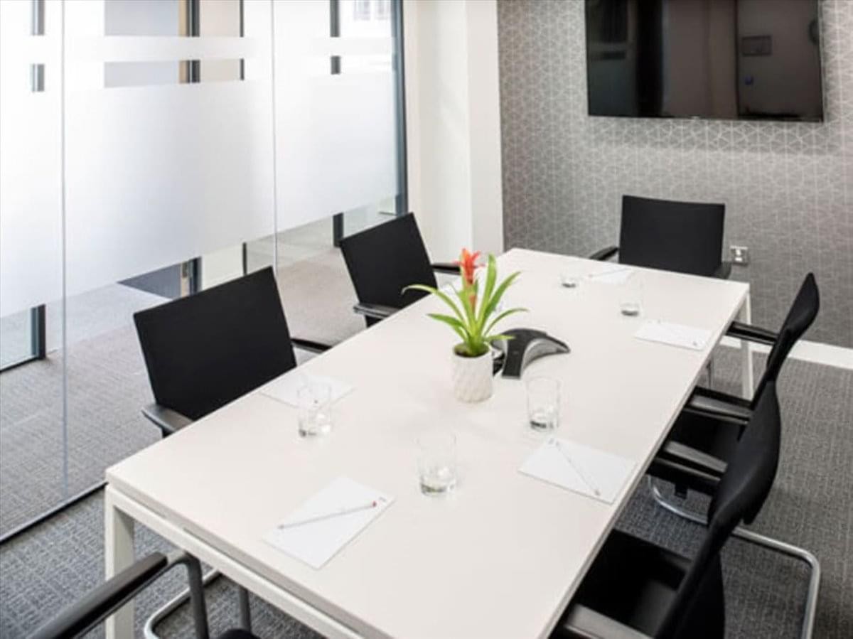 Meeting room at 2 Bloor Street West, Suite 700 with a white table and black chairs.