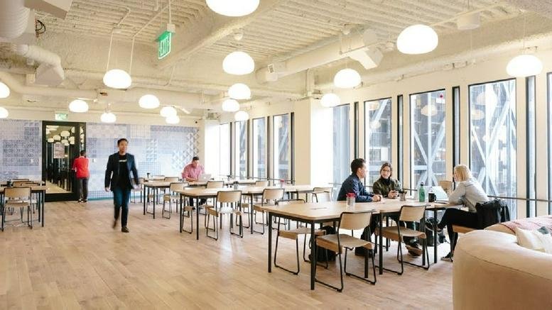 Spacious communal coworking area with round pendant lights at 2 Embarcadero Center, San Francisco.