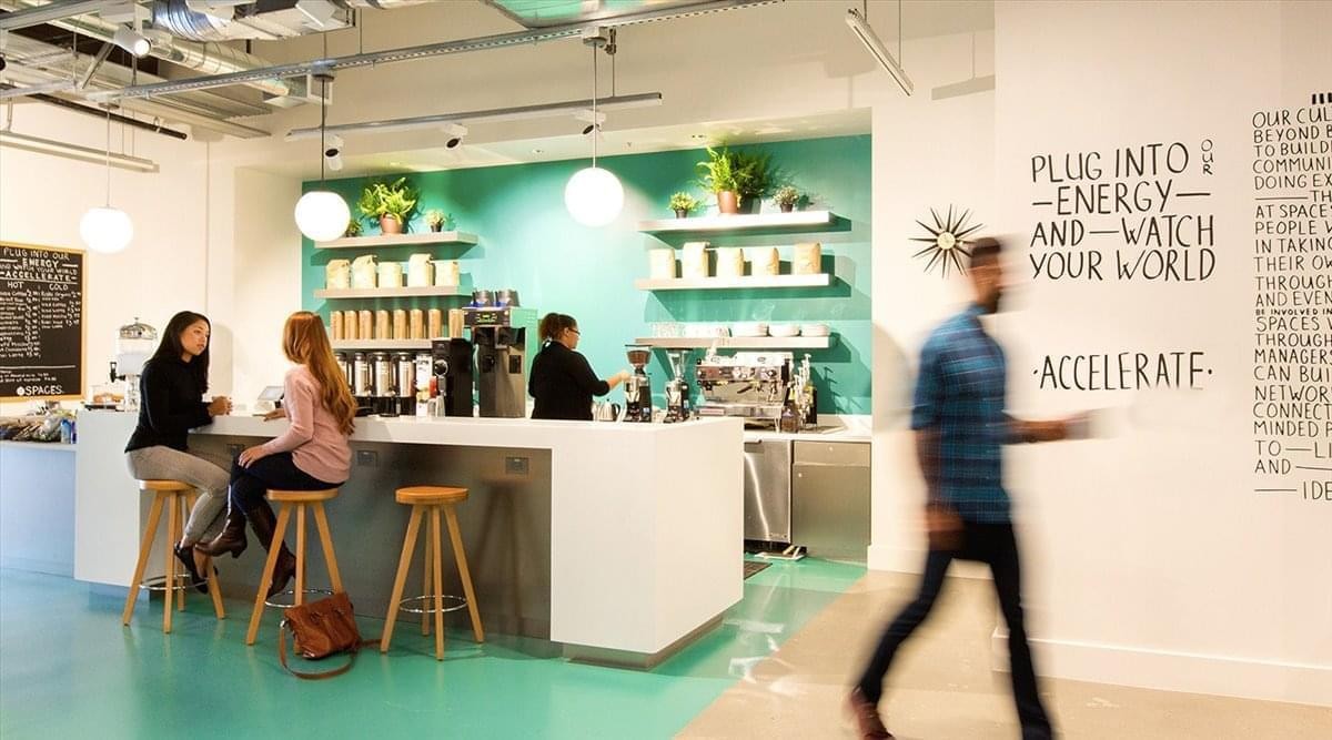 Spacious communal cafe area at 2 North Central Avenue with teal walls, white counters, and wood stools.