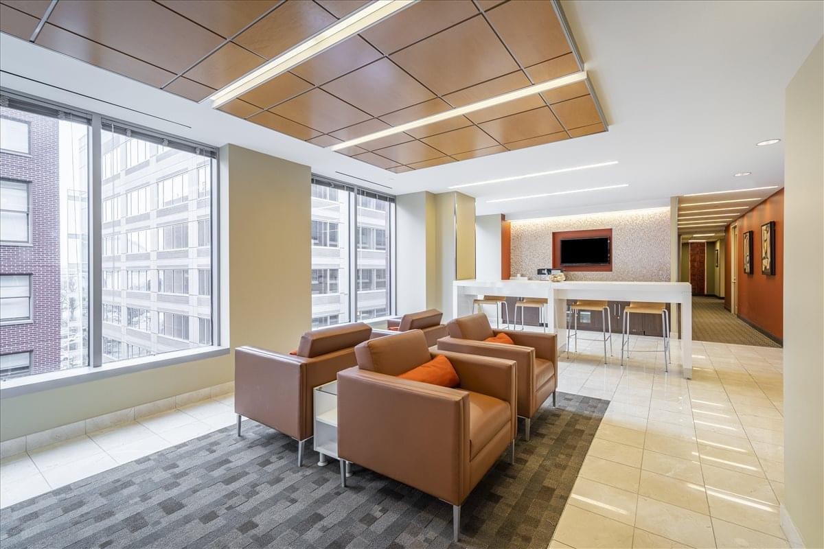 Bright breakout lounge with leather armchairs, large windows, and a high-top breakfast bar.