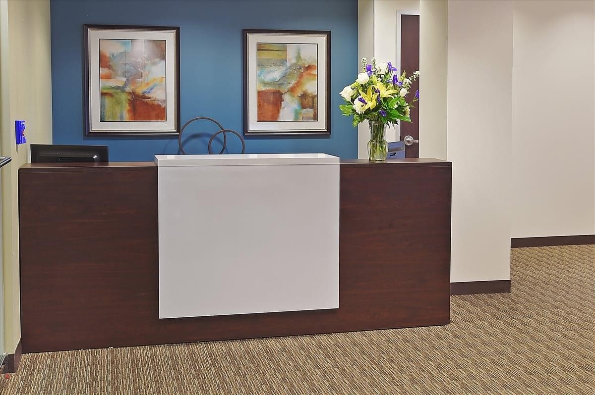 Modern reception desk with a blue feature wall and framed artwork.