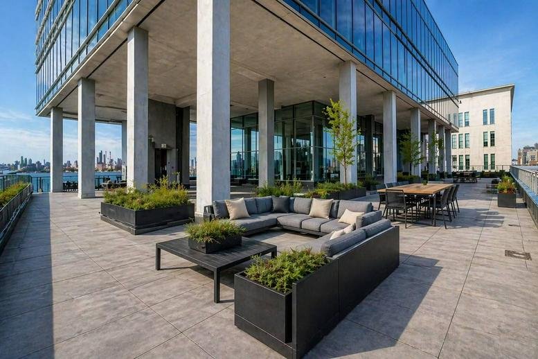 Sunlit outdoor lounge area at 200 Kent Avenue Offices with modern patio furniture.