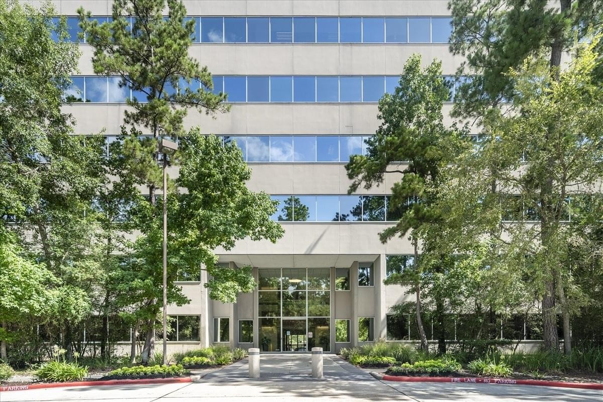 Exterior view of the office building at 2002 Timberloch Place surrounded by mature trees.