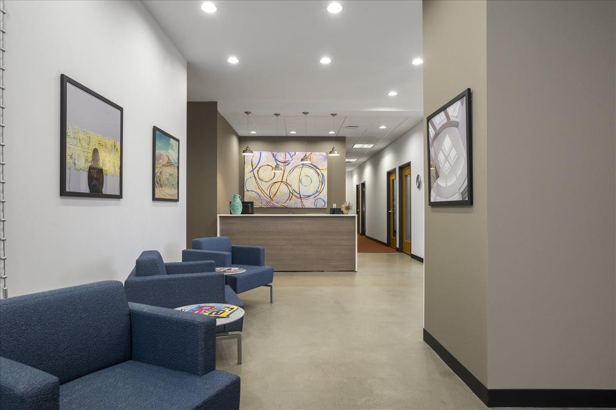 Spacious reception area at 2005 SE 192nd Avenue with blue armchairs, wall art, and a wooden front desk.