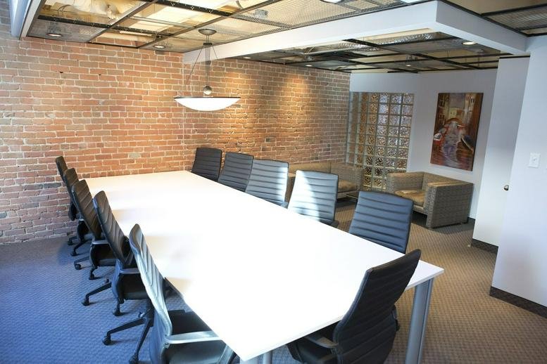 Spacious board room at 204 rue Saint-Sacrement, Suite 300 with a long white table and exposed brick.