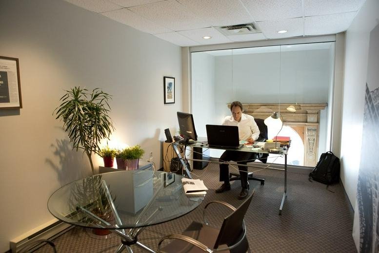 Brightly lit professional workspace at 204 rue Saint-Sacrement, Suite 300, showing a desk and glass partitions.