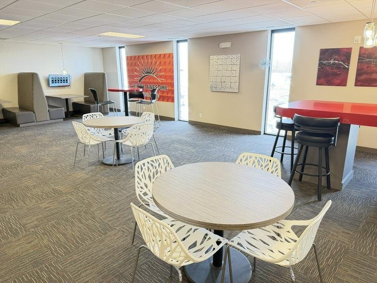 Spacious communal lounge at 2042 Wooddale Drive, Suite 250, with café tables and a vibrant sun mural.