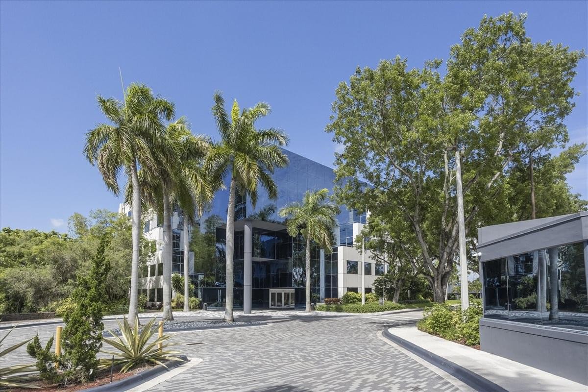 Palm trees surrounding the glass-facade exterior of the Aventura Corporate Center.