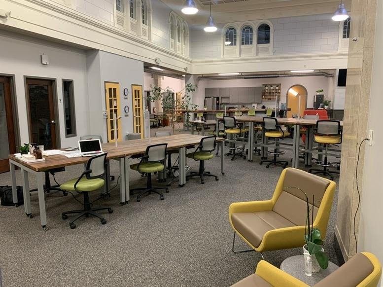 Spacious communal coworking area at 2081 Center Street, Berkeley, California with yellow accent chairs and wood tables.