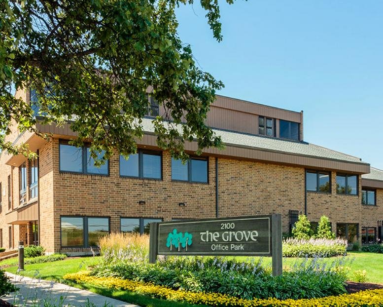Exterior view of the brick facade and landscaped signage at 2100 Manchester Rd, Wheaton, Illinois.