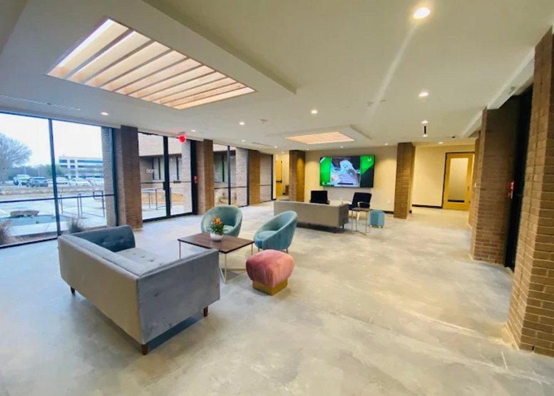 Spacious lobby at HEXA Coworking featuring modern seating, a pink ottoman, and natural light from a skylight.