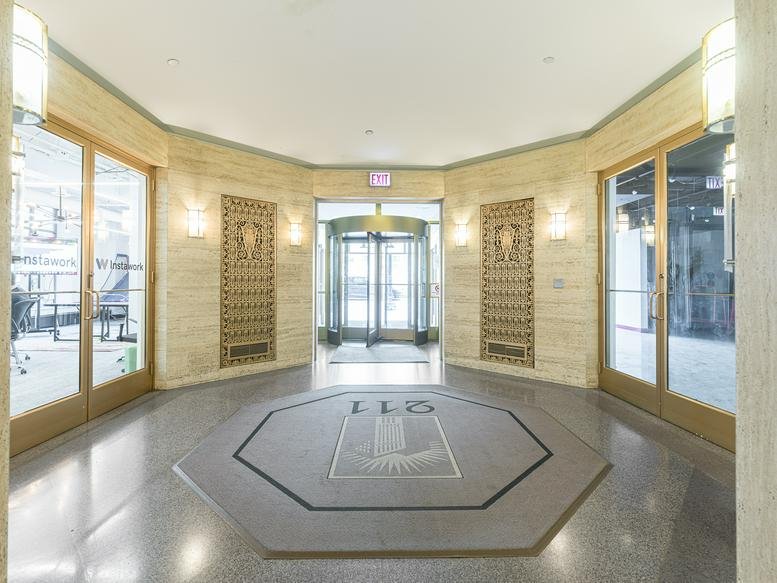 Grand building entrance at 211 W Wacker Drive featuring stone walls and revolving doors.