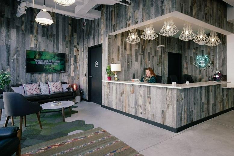 Reception area at 2120 University Ave with reclaimed wood walls and modern geometric pendant lights.