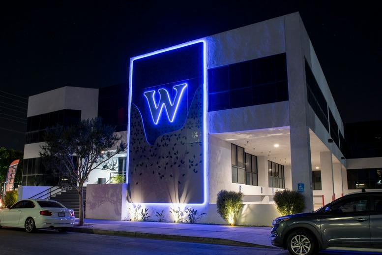 Exterior view of the white facade and glowing blue 'W' signage at W Executive Suites.