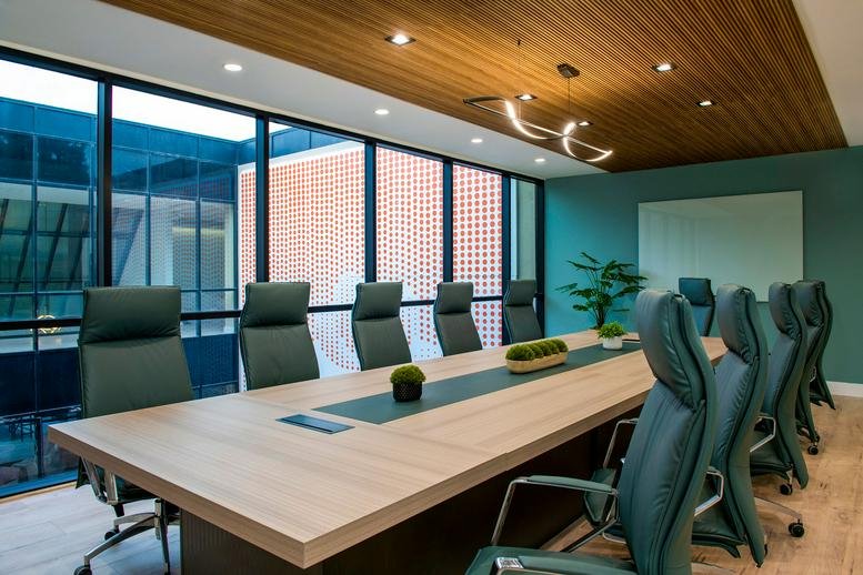 Large meeting room with a long wood table, green chairs, and floor-to-ceiling windows.