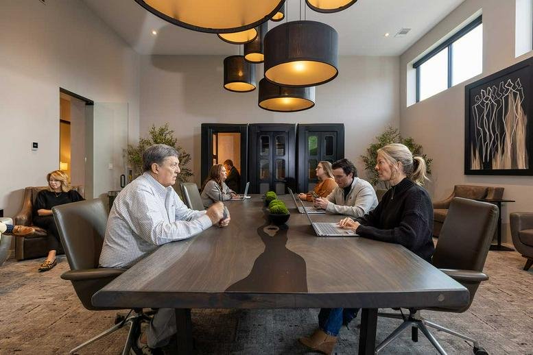 Spacious communal lounge at 216 Coworking with a live-edge wooden table and designer pendant lights.