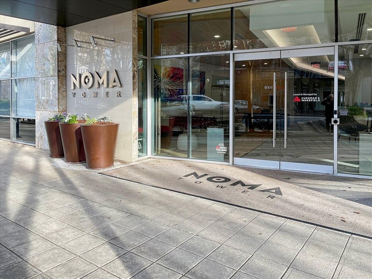 Street-level entrance of the Downtown NOMA Tower Business Center with glass doors and planters.