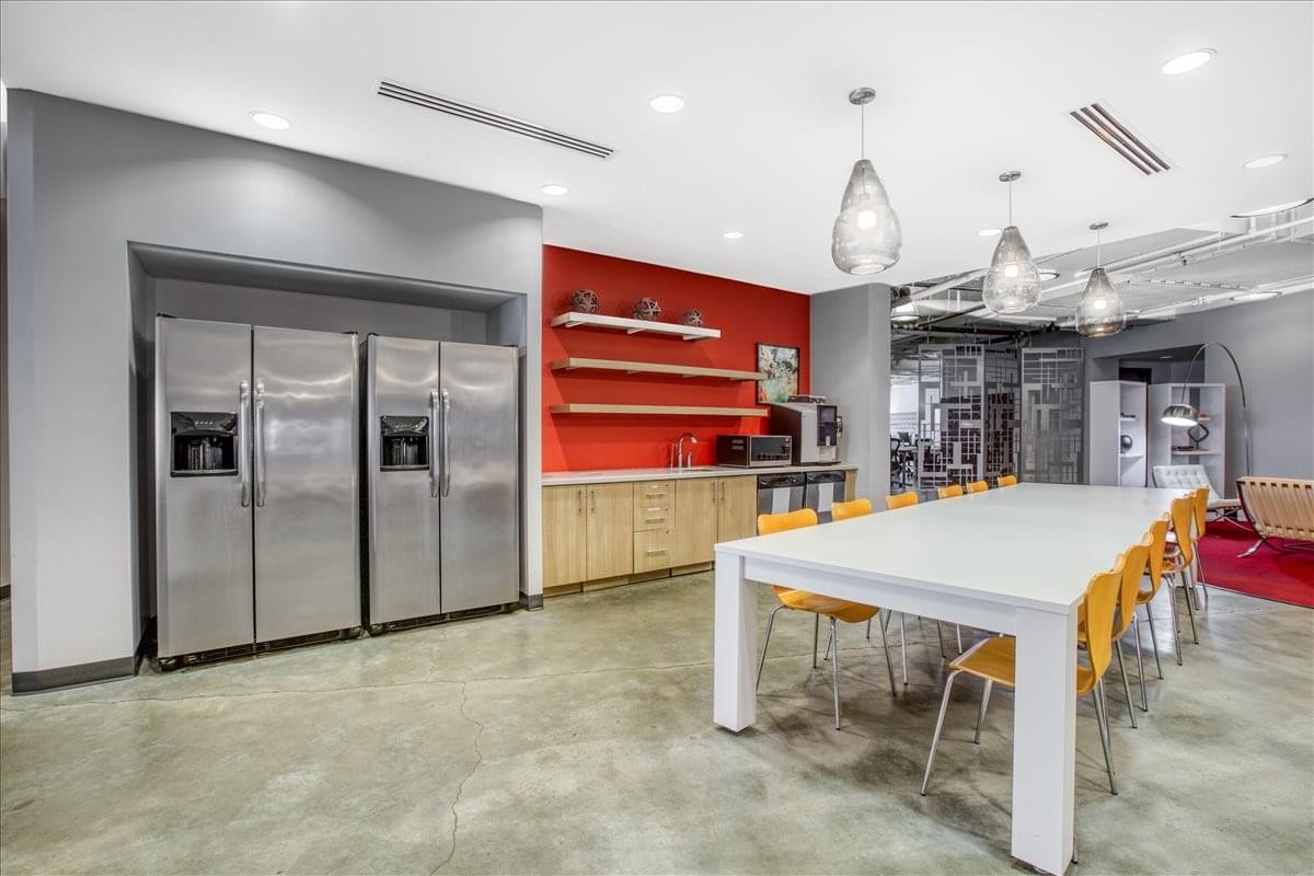 Bright kitchen and break area with stainless steel fridges and a red accent wall.