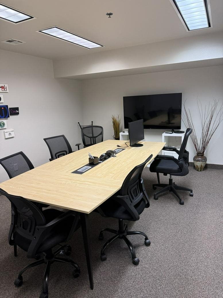 Professional meeting room at Boise Main Coworking Space with a large table, TV, and whiteboard.